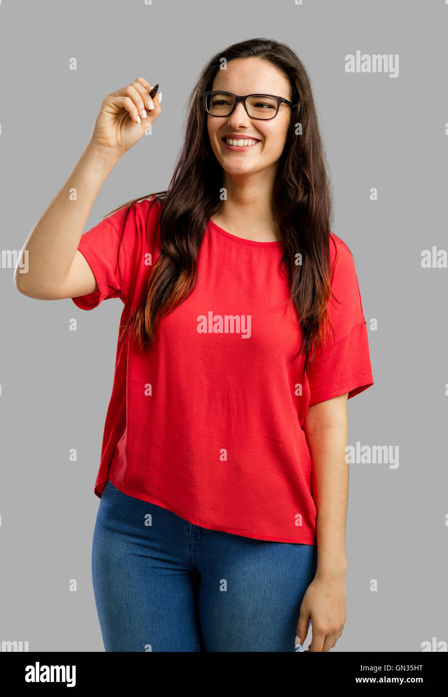 Happy woman writing something on a glass board, isolated over a gray background Stock Photo