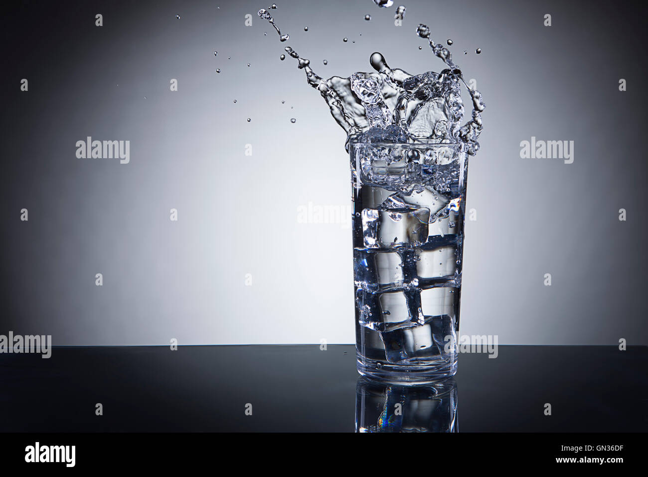 Ice dropped in water glass Stock Photo - Alamy