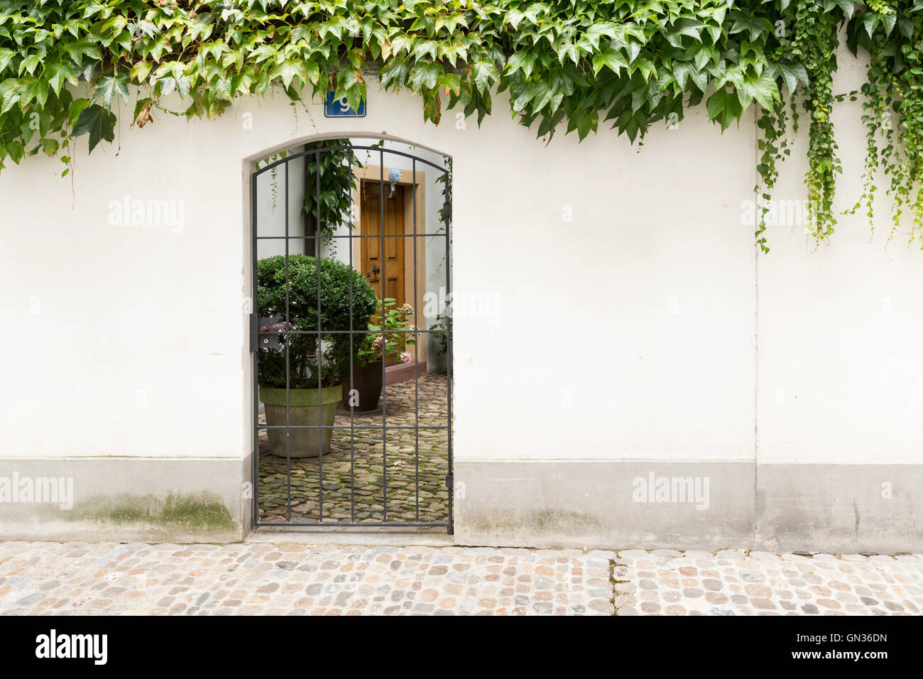 View through a gate with metal bars inside a cute little courtyard. Stock Photo