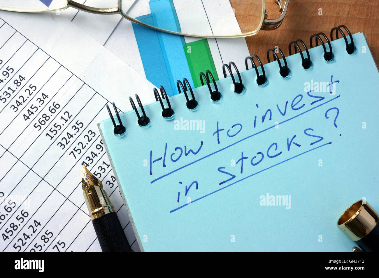 Notepad with inscription  how to invest in stocks on a table. Stock Photo