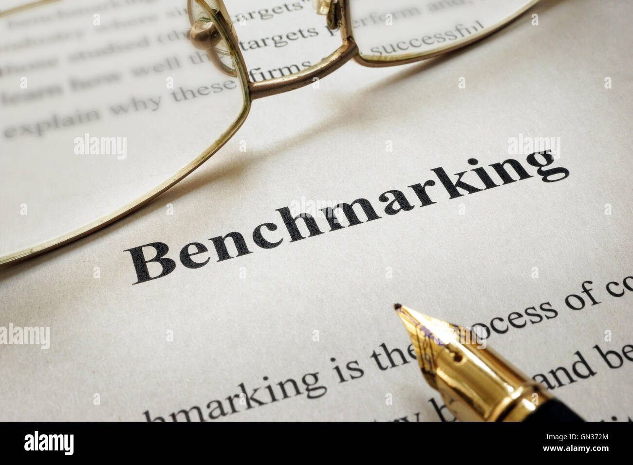 Page of paper with words Benchmarking and glasses. Stock Photo