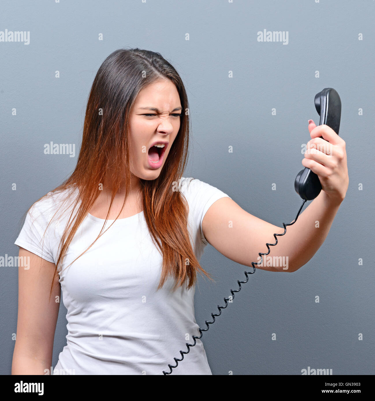 Portrait of woman having unpleasant phone calll against gray background  Stock Photo - Alamy