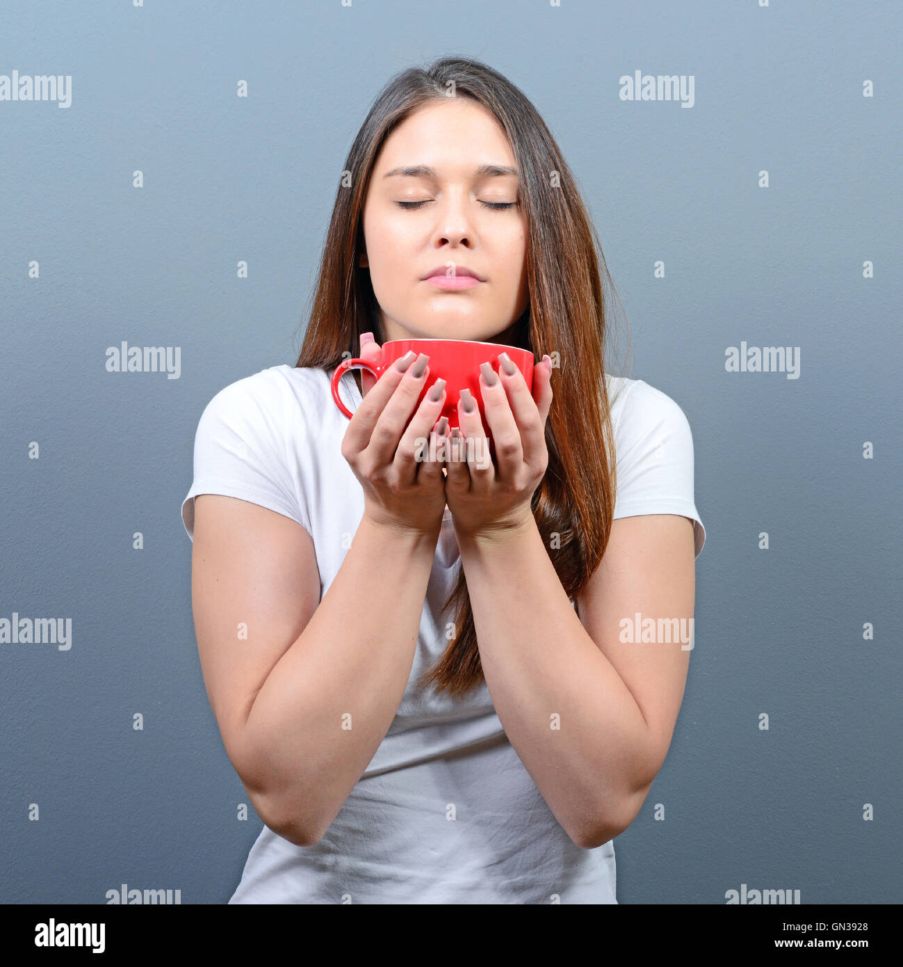 Woman enjoying aroman of hot beverage against gray background Stock Photo -  Alamy