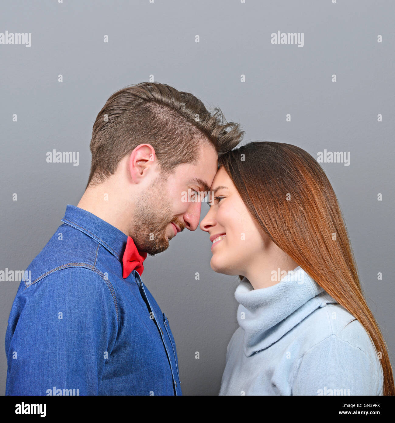 Happy couple in love looking deeply into each others eyes against gray background Stock Photo