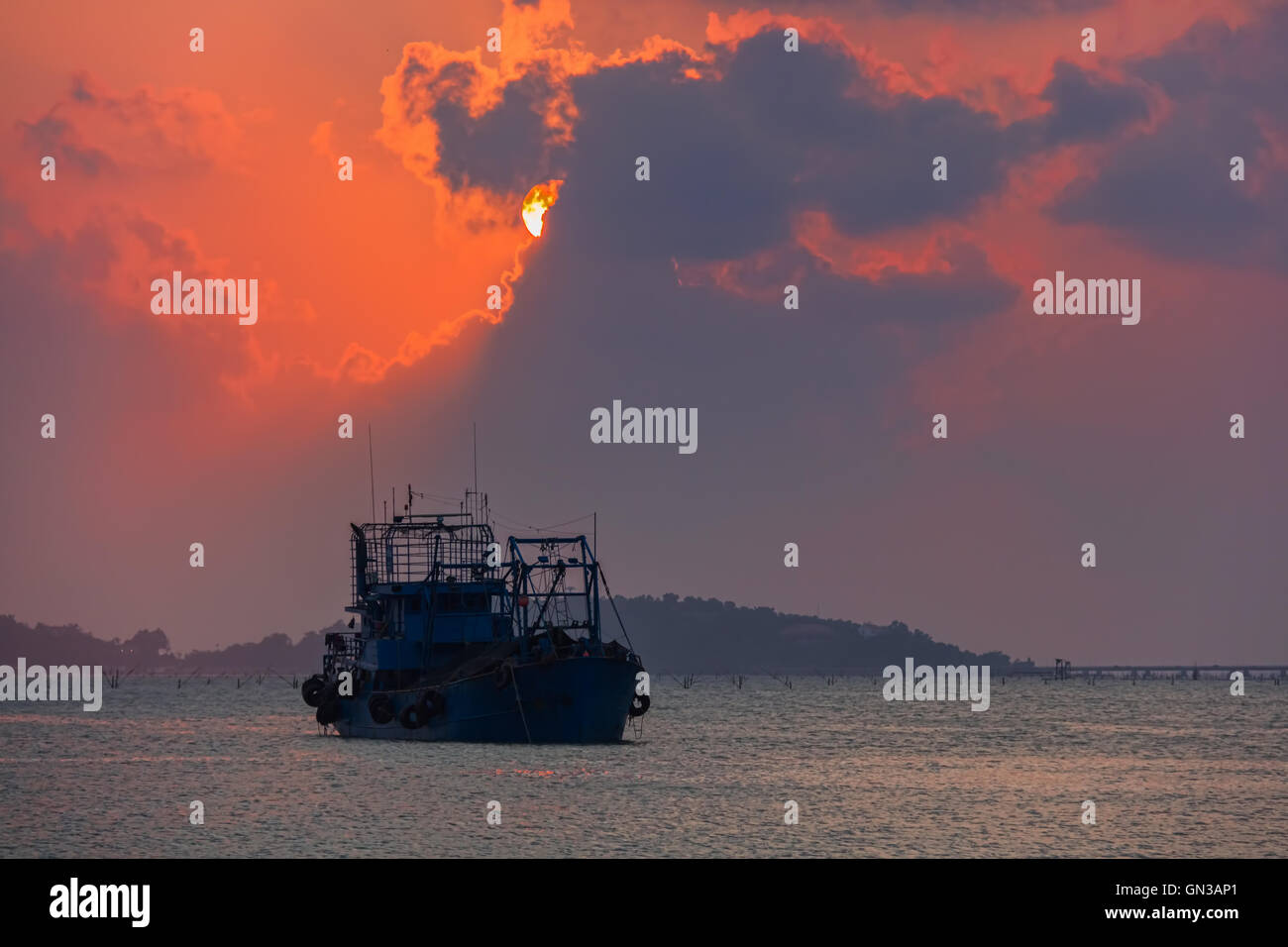 Sunset light sky clouds colorful sea fishing boat. Stock Photo