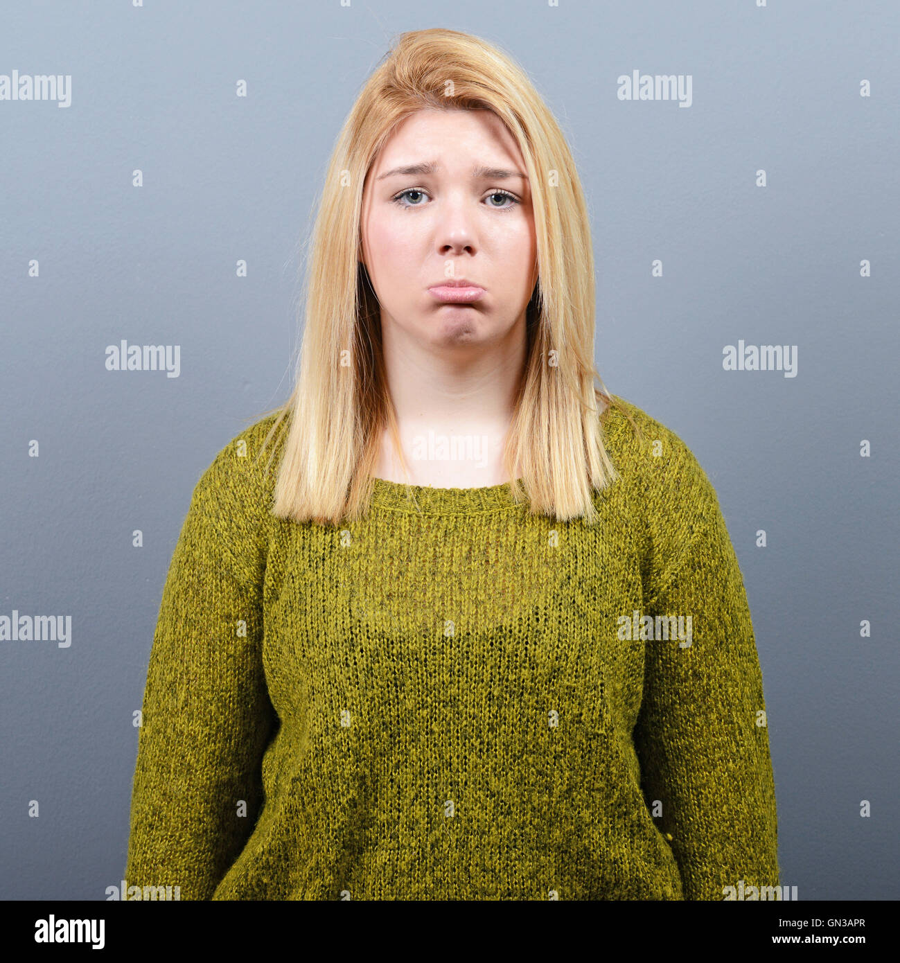 Portrait of a sad woman against gray background Stock Photo - Alamy