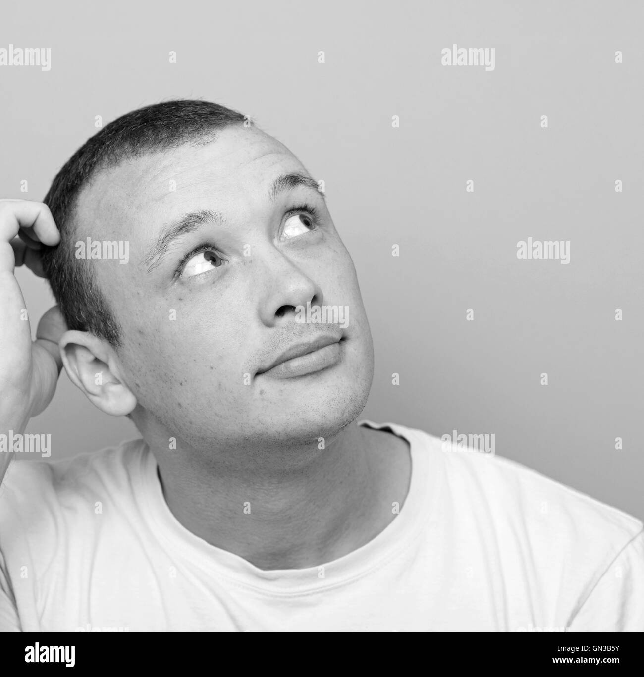 Portrait of confused man against green background looking up Stock Photo