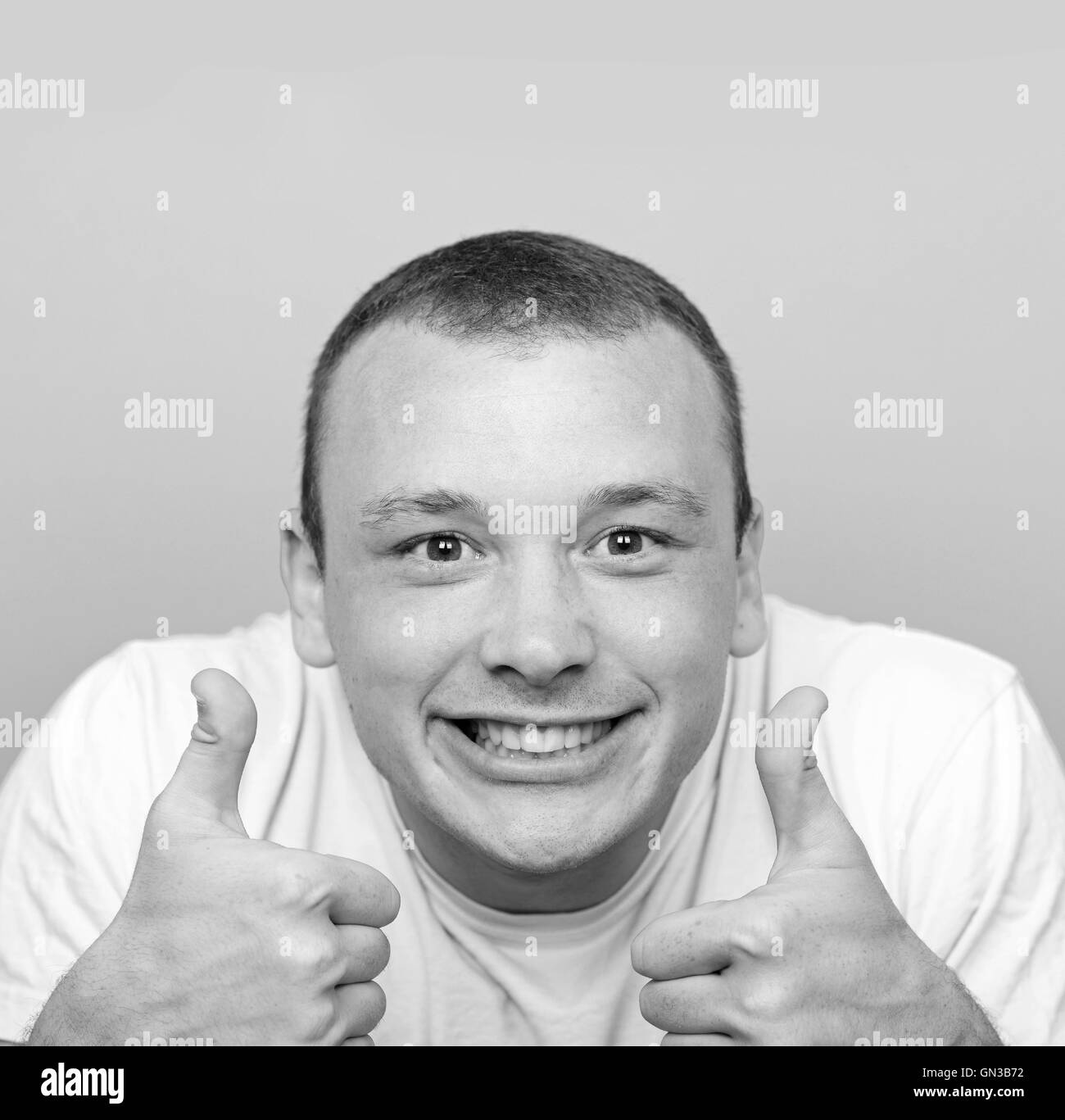 Portrait of with funny expression holding thumbs up against green background Stock Photo