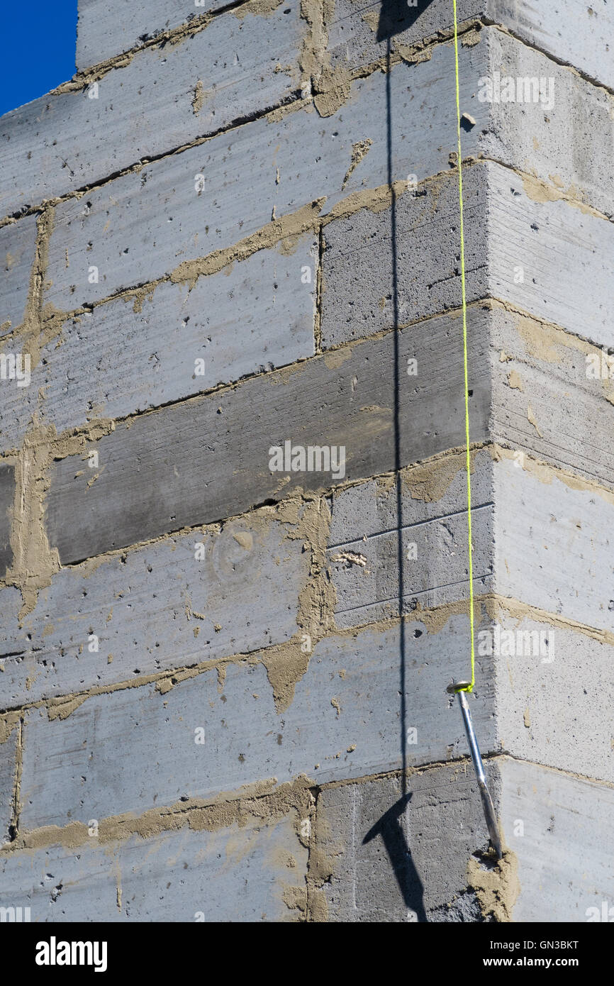 Builder's plumb line hanging against exterior corner wall of house