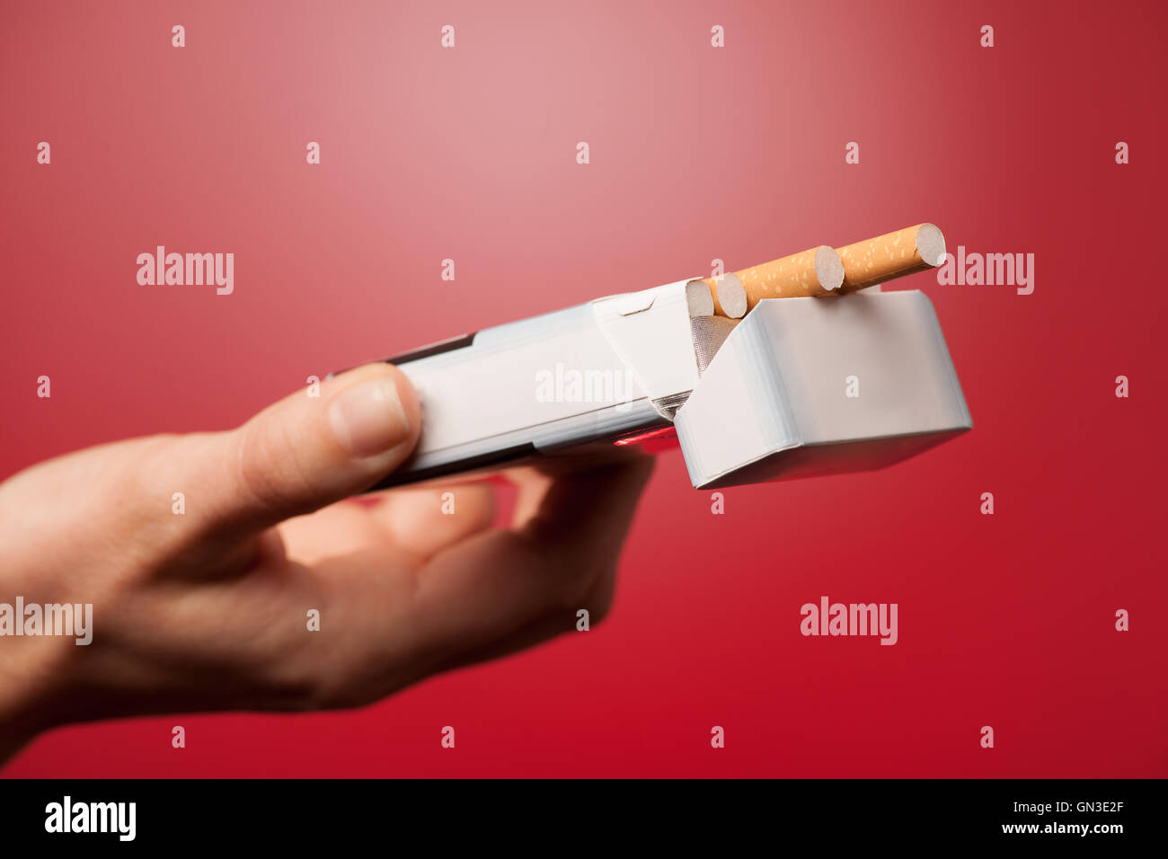 woman offering a cigarette over red background Stock Photo