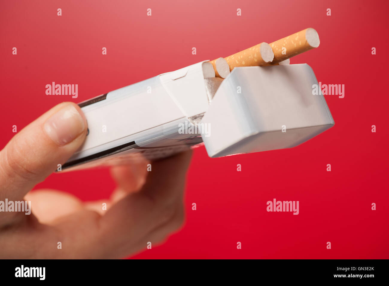 woman offering a cigarette over red background Stock Photo