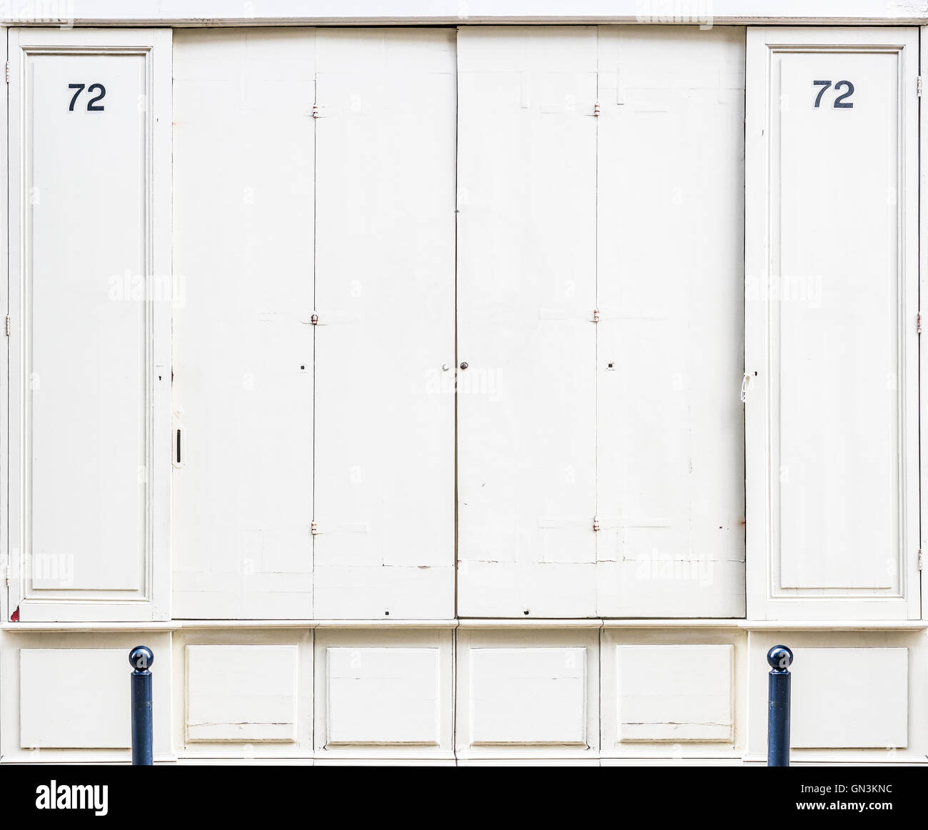 Antique white wooden doors of a store with a number 72 in both sides. Antique european style. Stock Photo