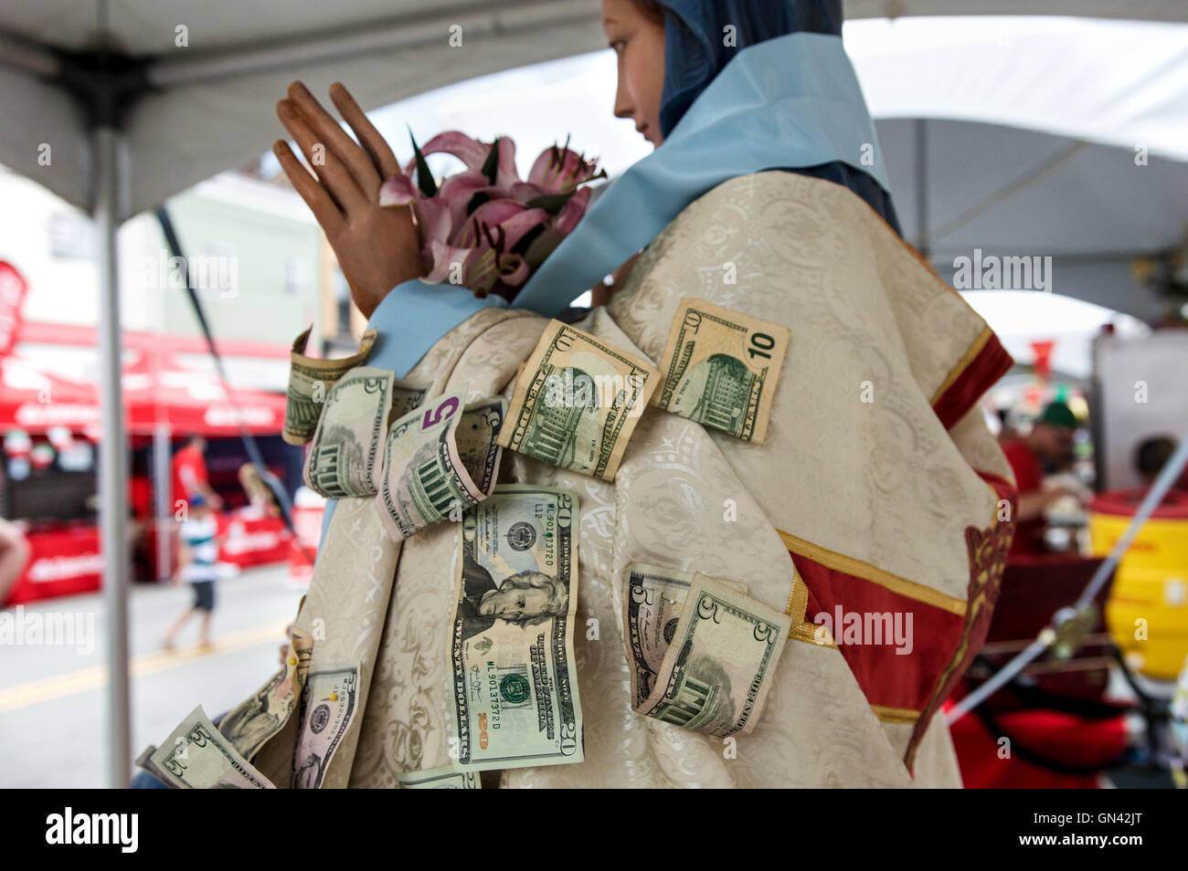 Dollar bills are pinned to a statue of the Virgin Mary at the Little Italy Festival in Pittsburgh's Bloomfield neighborhood. Stock Photo