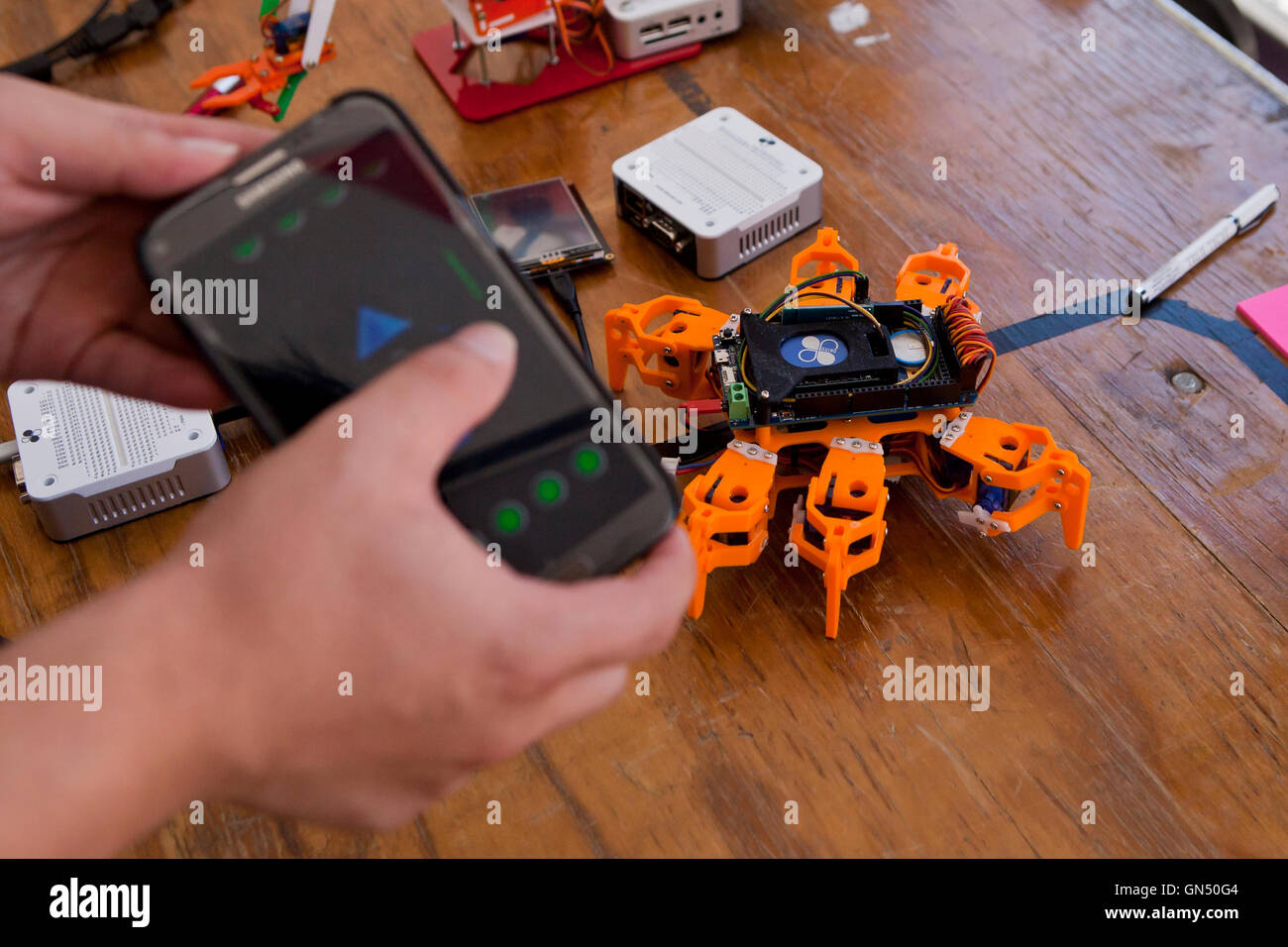 Man controlling toy robot with mobile phone ap via bluethooth - USA Stock Photo