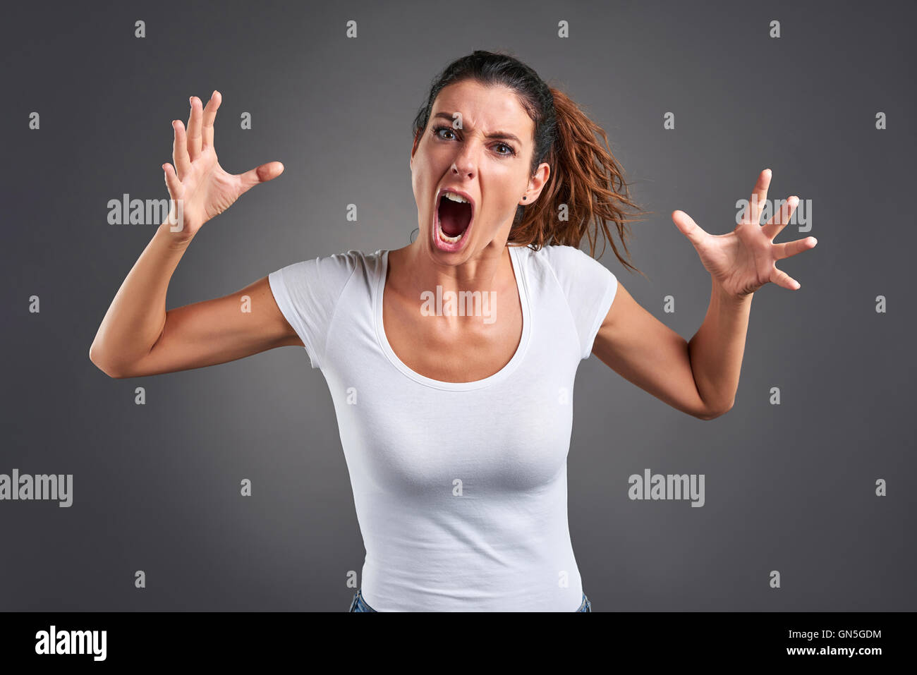 A beautiful young woman screaming furiously. Stock Photo