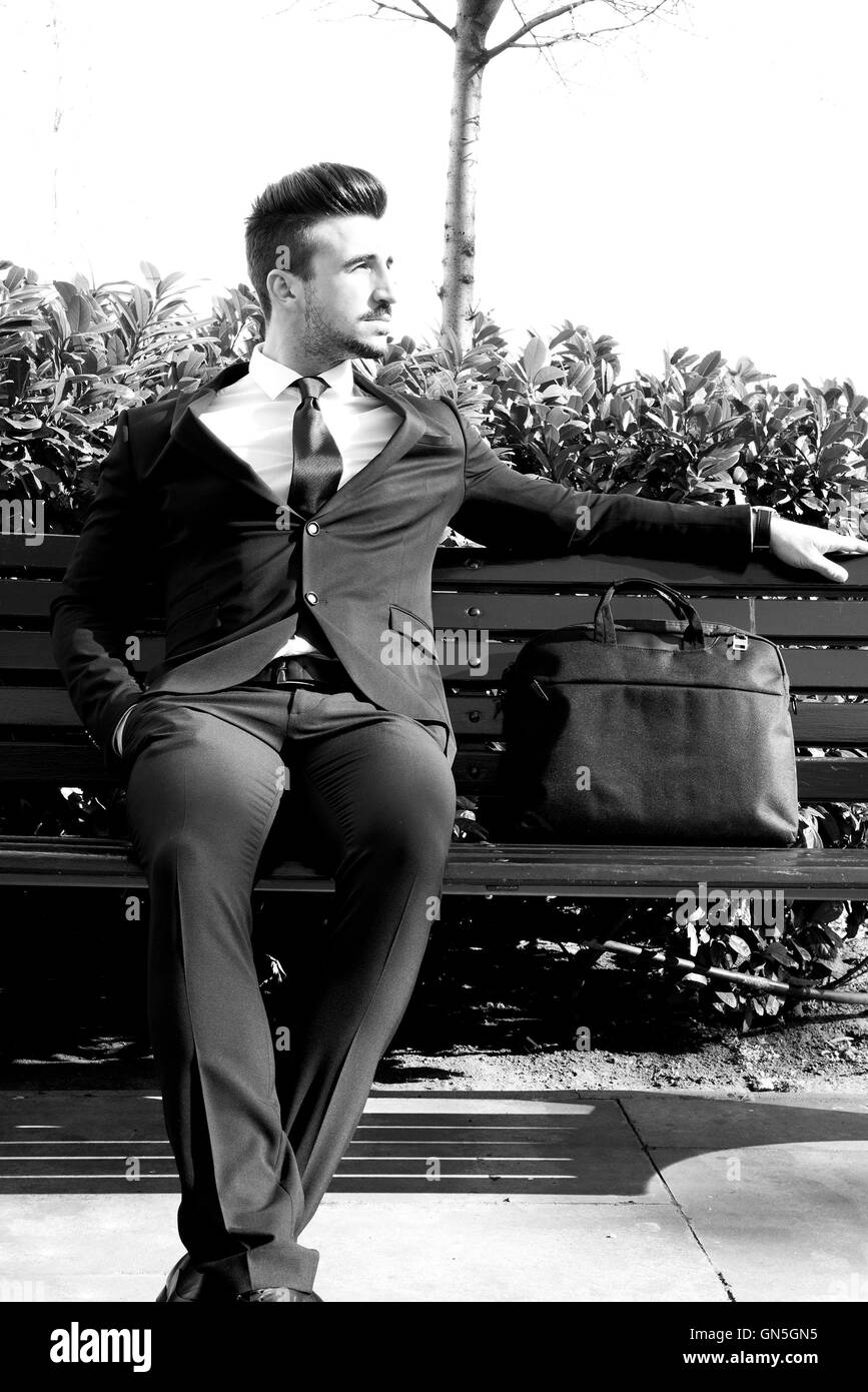 Portrait of a young businessman sitting on a bench Stock Photo - Alamy