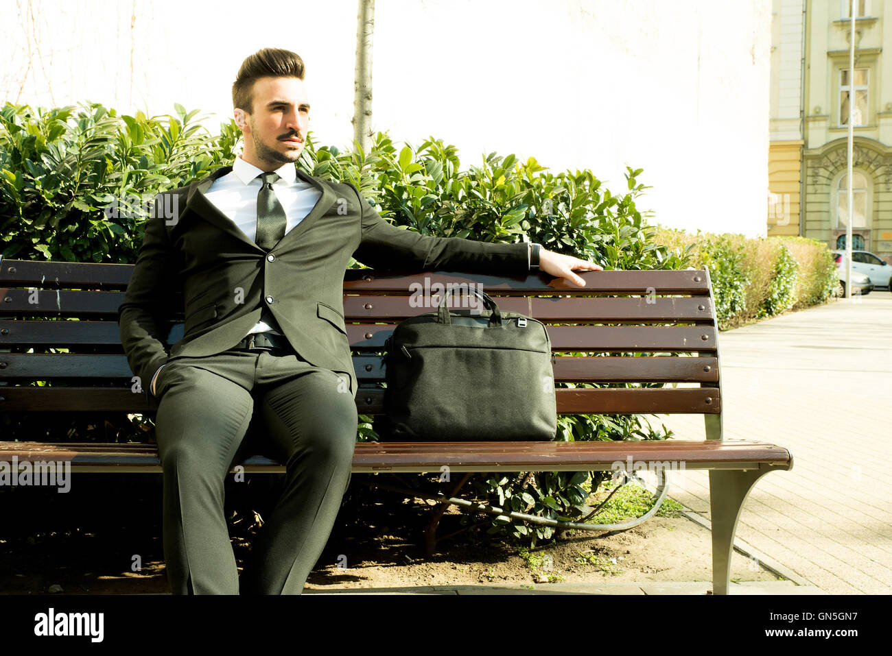 Portrait of a young businessman sitting on a bench Stock Photo - Alamy