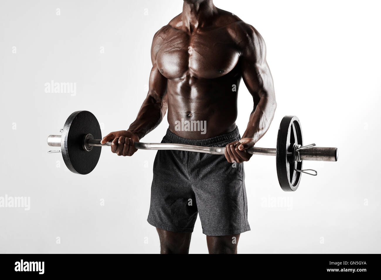 Cropped shot of african male exercising with barbell. Muscular young man exercising with weights over grey background. Stock Photo