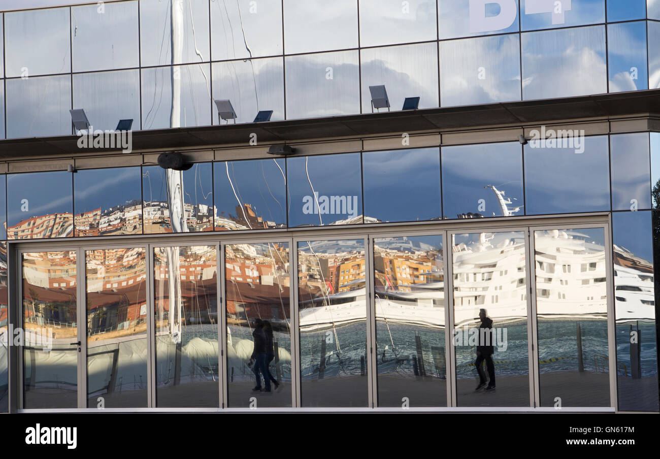 Reflected people in a building glass, walking in the harbor Stock Photo