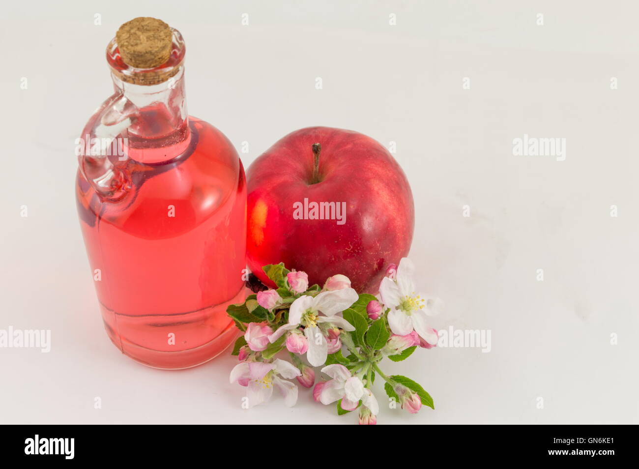 Red apple and apple vinegar decorated with flowers Stock Photo