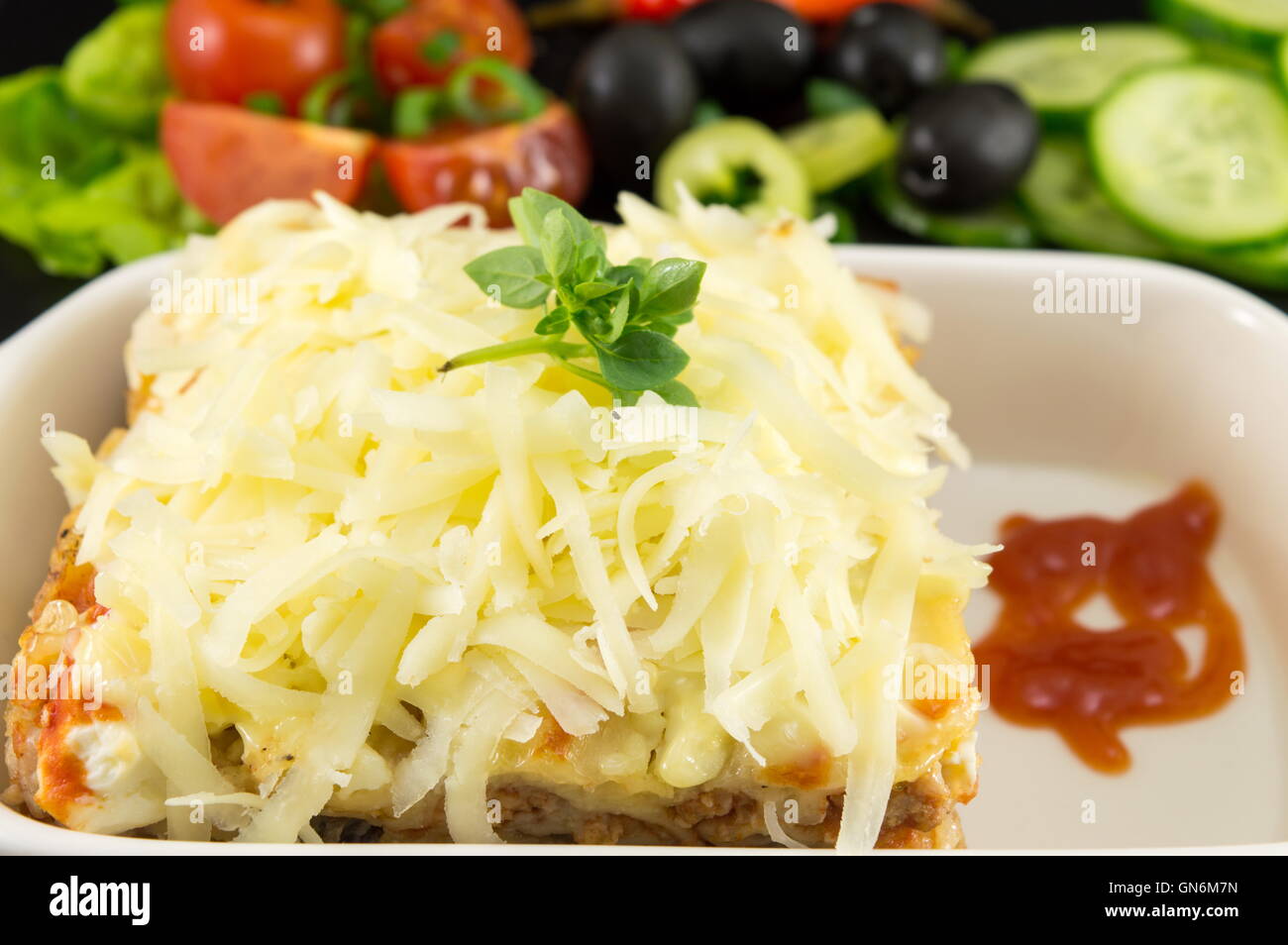Lasagna portion served with fresh vegetables close up Stock Photo