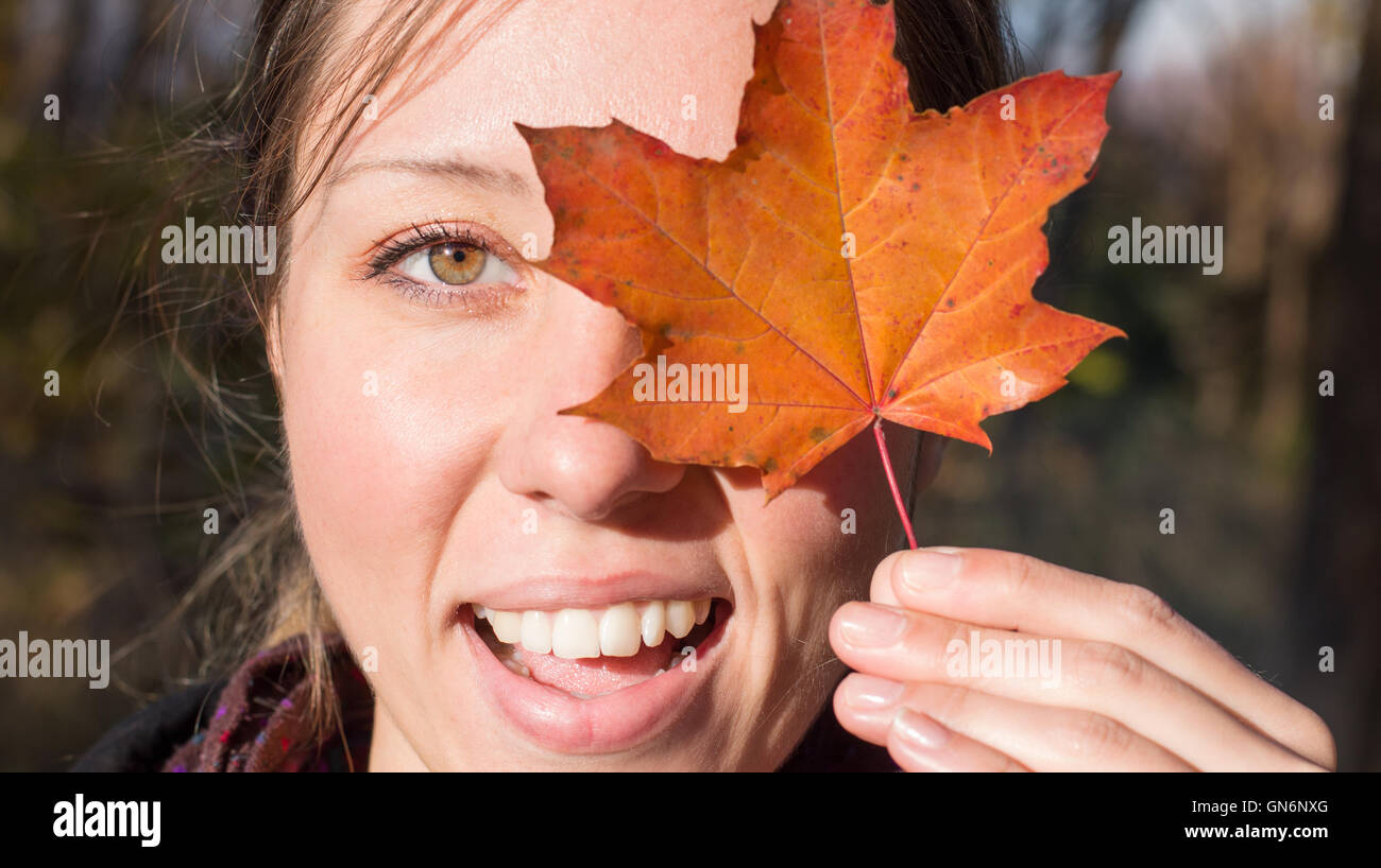 Happy woman holding autumn leaf in the park Stock Photo - Alamy