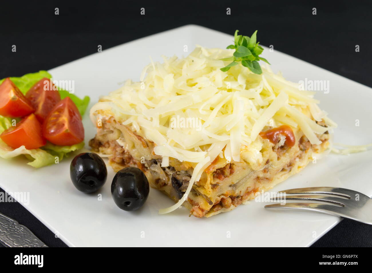 Lasagna portion served with fresh vegetables on a plate Stock Photo