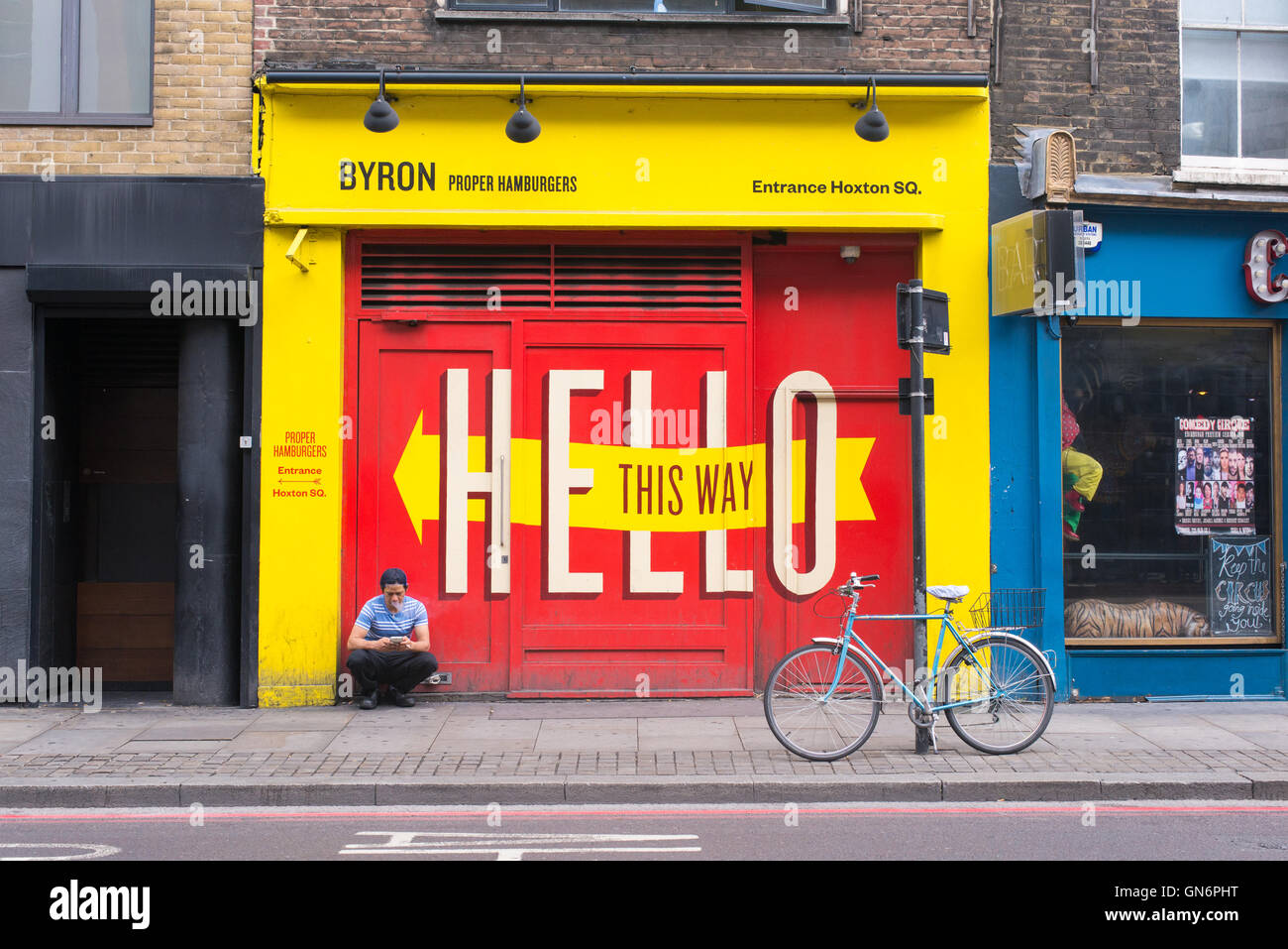 Guy sitting in front of a closed branch of Byron, a popular British burger restaurant chain with several restaurants in London. Stock Photo