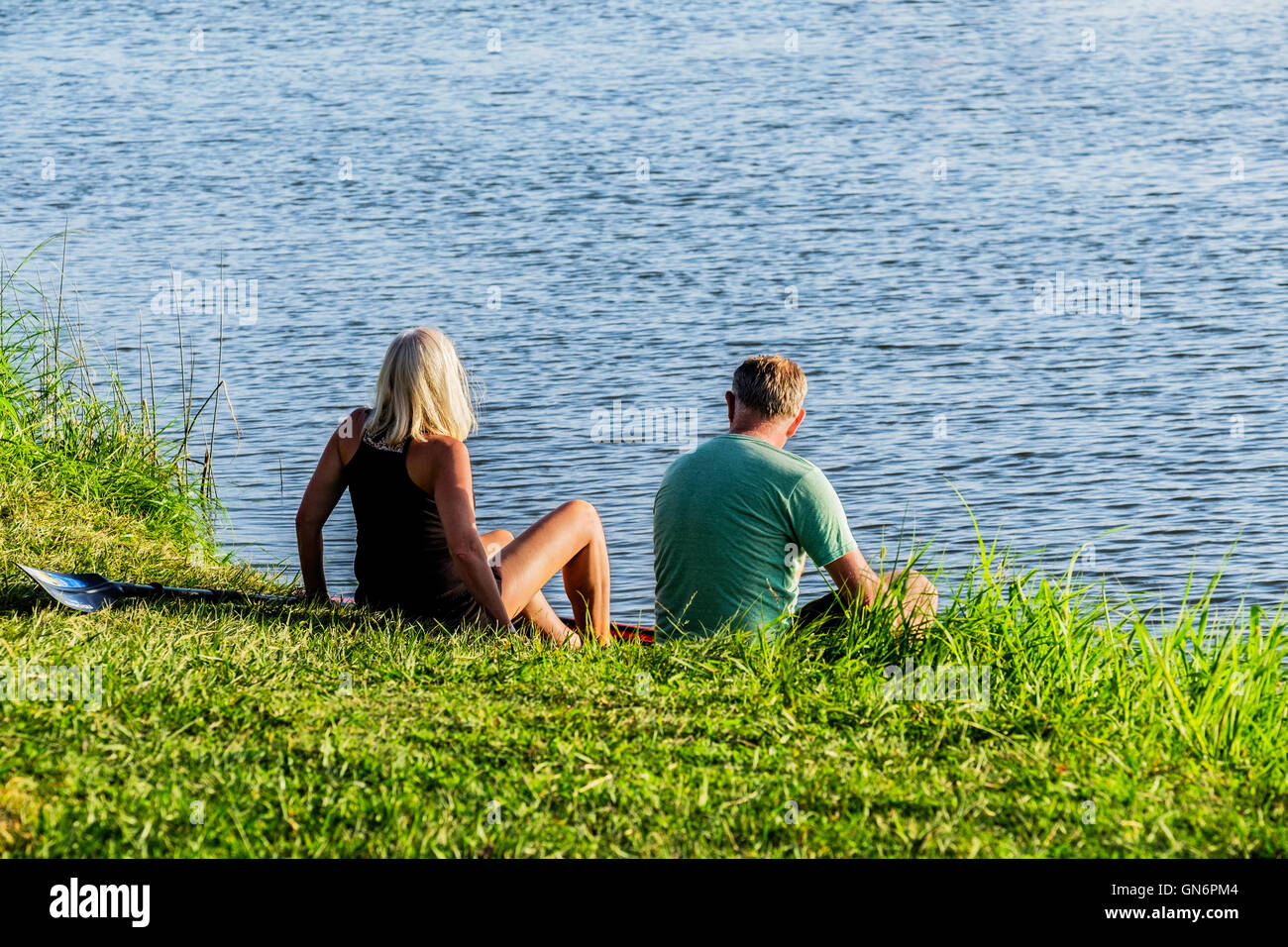 A middle aged Caucasian man and woman prepare to get in a conoe on the North Canadian river in evening light. Oklahoma, USA. Stock Photo