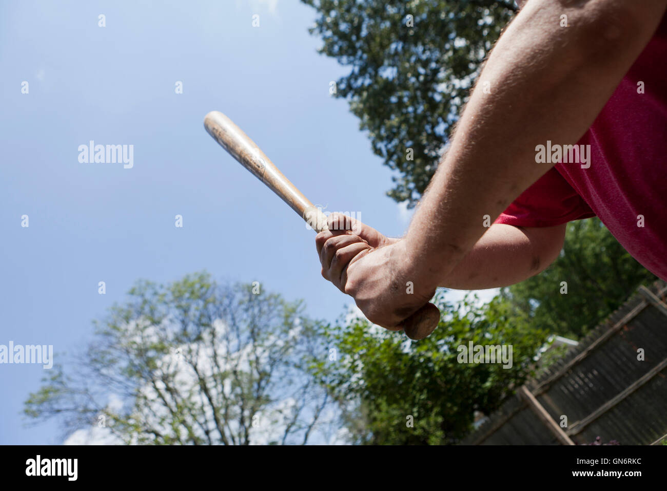 Man holding a wooden baseball bat preparing to swing in self