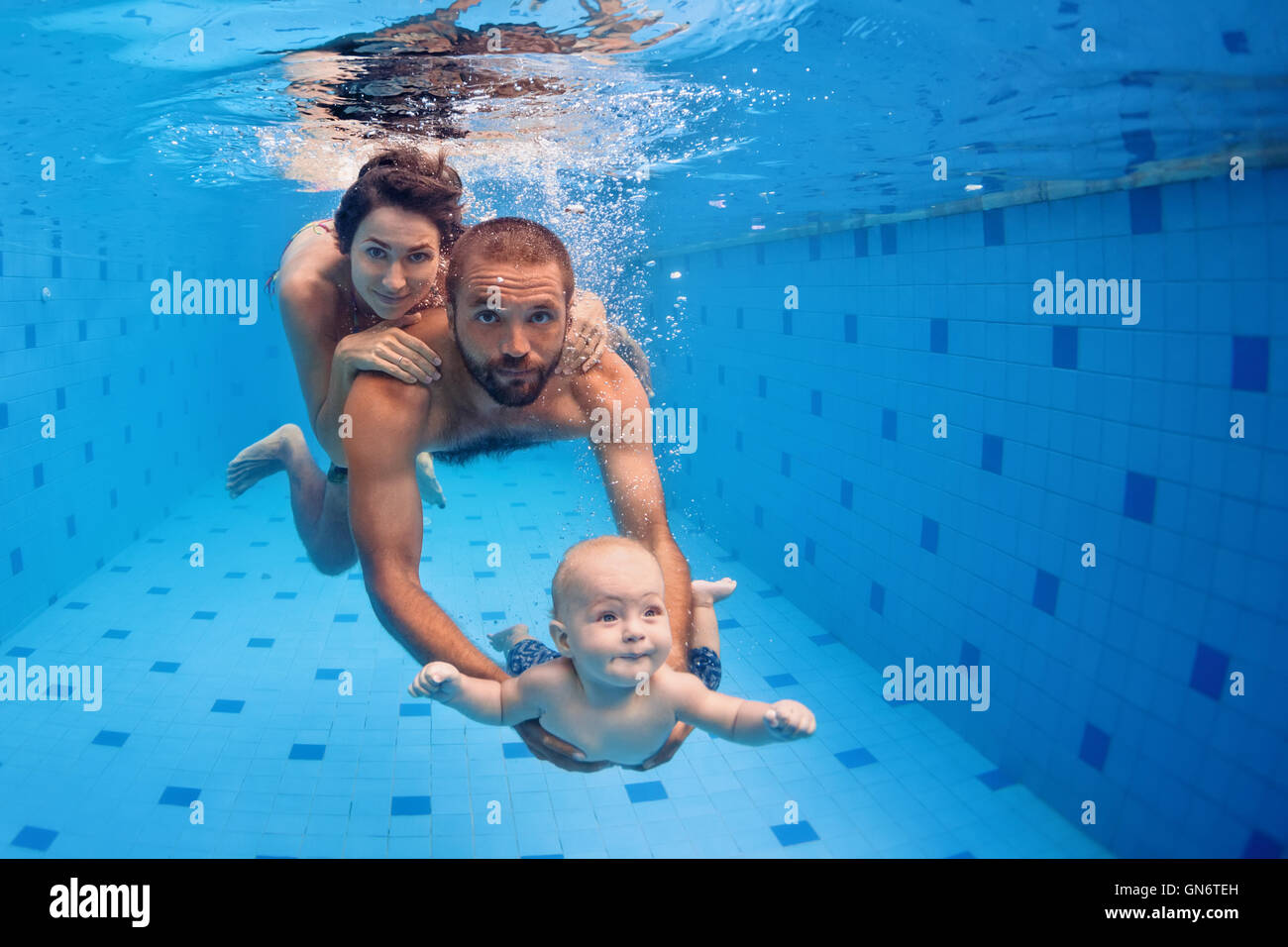 Family fitness mother, father, baby son learn to swim together, dive