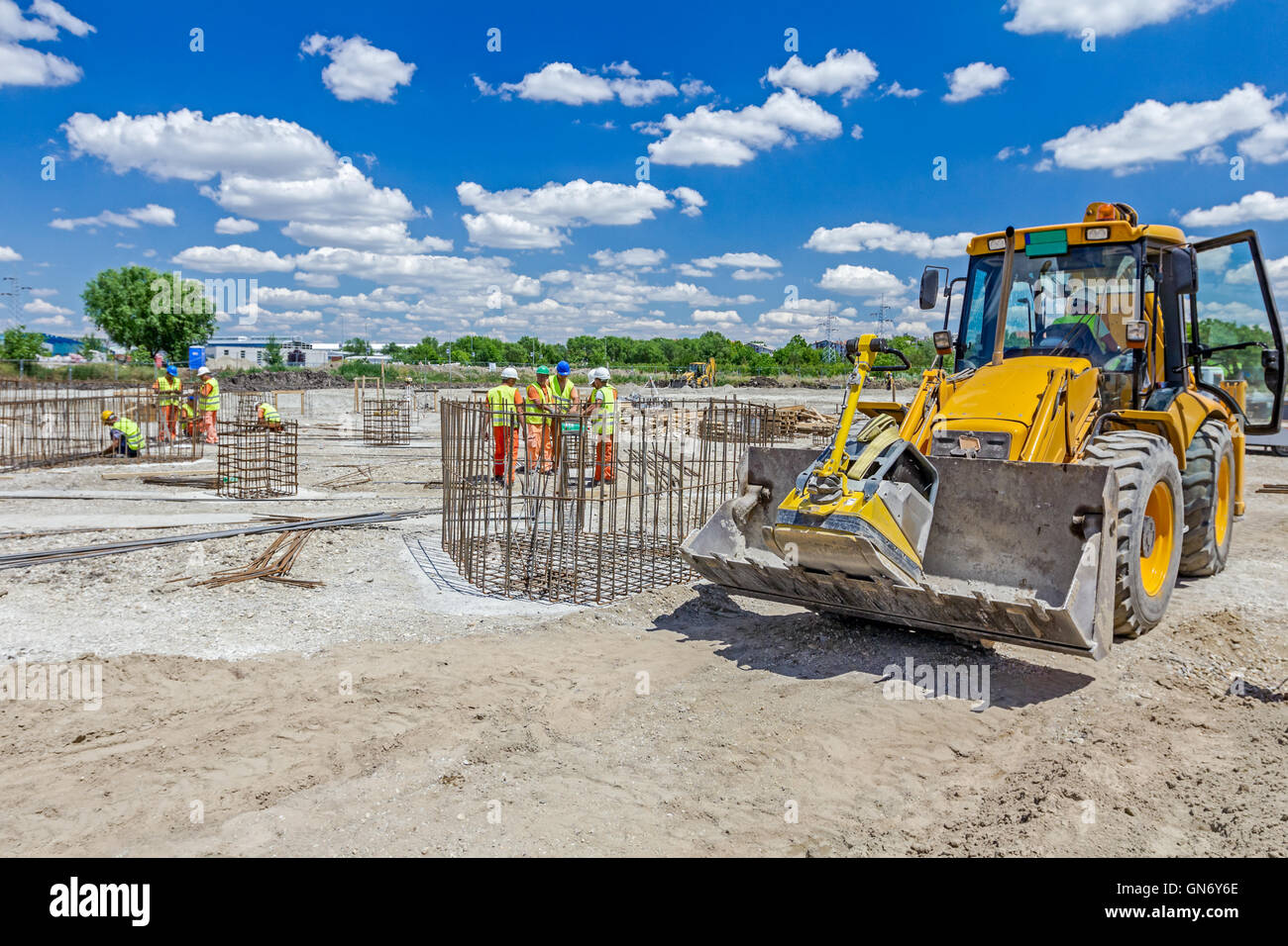 Excavator is moving over building site with raised up front bucket