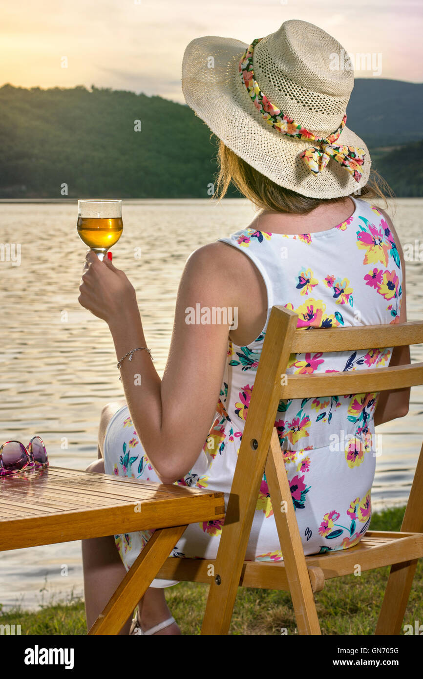 Woman having a glass of wine by the lake Stock Photo
