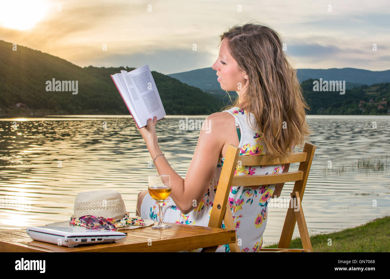 Young woman reading a book by the lake Stock Photo