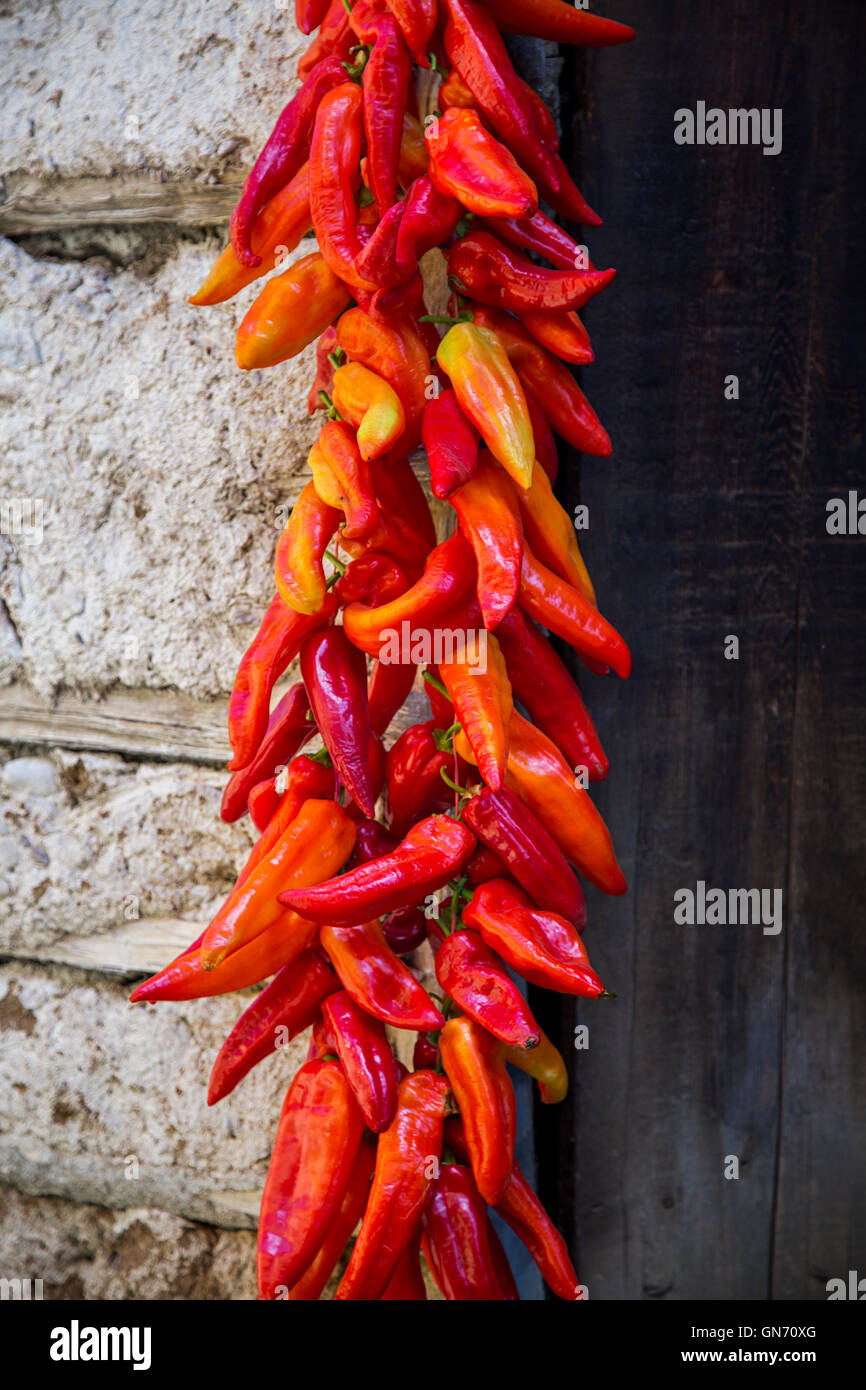 Red Paprika Peppers traditionally hanging To Dry On The Wall Of A House Stock Photo