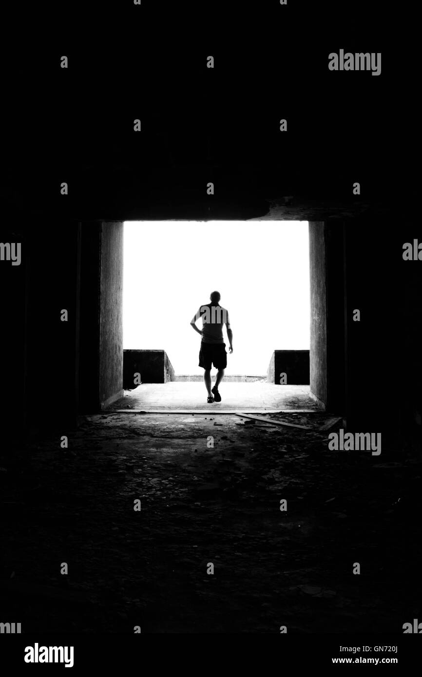 A black and white silhouette of a man on the end of a tunnel in an abandoned hotel in São Miguel, Azores. Stock Photo