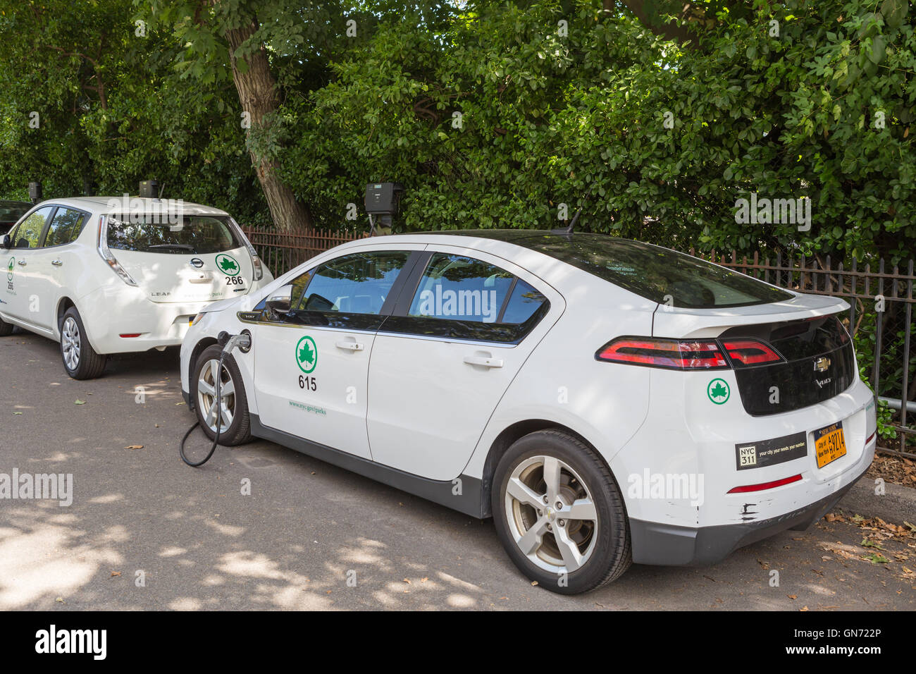 New York City Parks department Chevy Volt and Nissan Leaf electric cars receive a charge at a charging station in Central Park. Stock Photo