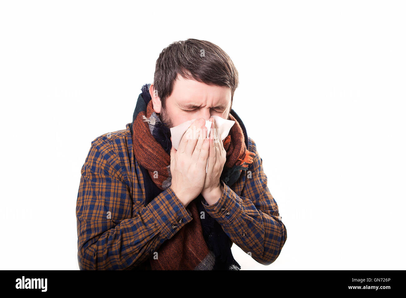 young sick and ill man in bed holding tissue cleaning snotty nose having temperature feeling bad infected by winter grippe virus in flu and influenza health care concept Stock Photo