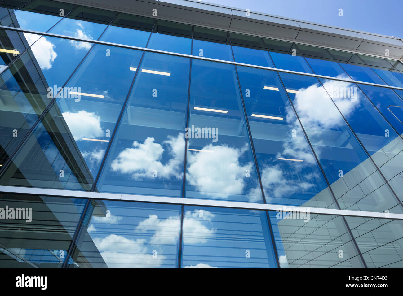 PUFFY WHITE CLOUDS BLUE SKY REFLECTED ON GLASS OFFICE BUILDING WINDOWS Stock Photo