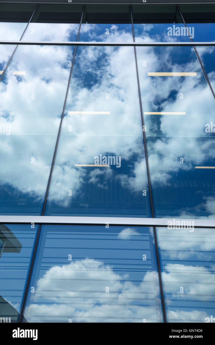 PUFFY WHITE CLOUDS BLUE SKY REFLECTED ON GLASS OFFICE BUILDING WINDOWS Stock Photo