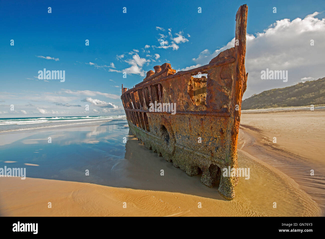 Coastal landscape with rusting remains of historic Maheno shipwreck on sandy 75-mile beach under blue sky on Fraser Island Australia Stock Photo