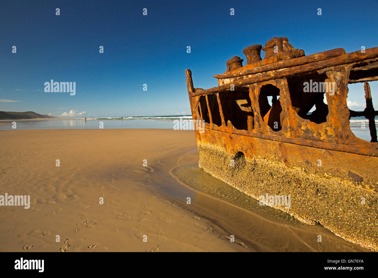 Rusting remains of historic Maheno shipwreck on sandy 75-mile beach under blue sky on Fraser Island Australia Stock Photo