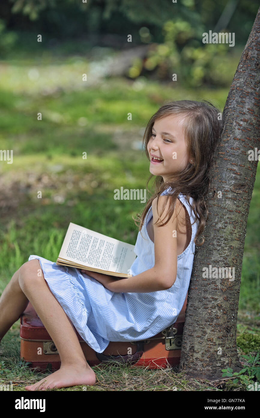 Young girl experiencing positive emotions by reading a book Stock Photo