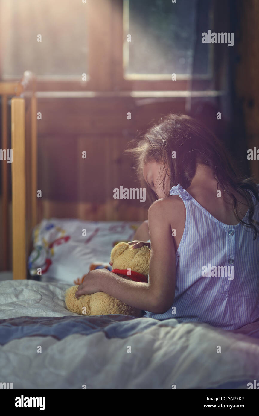 distraught little girl cuddles a teddy bear Stock Photo