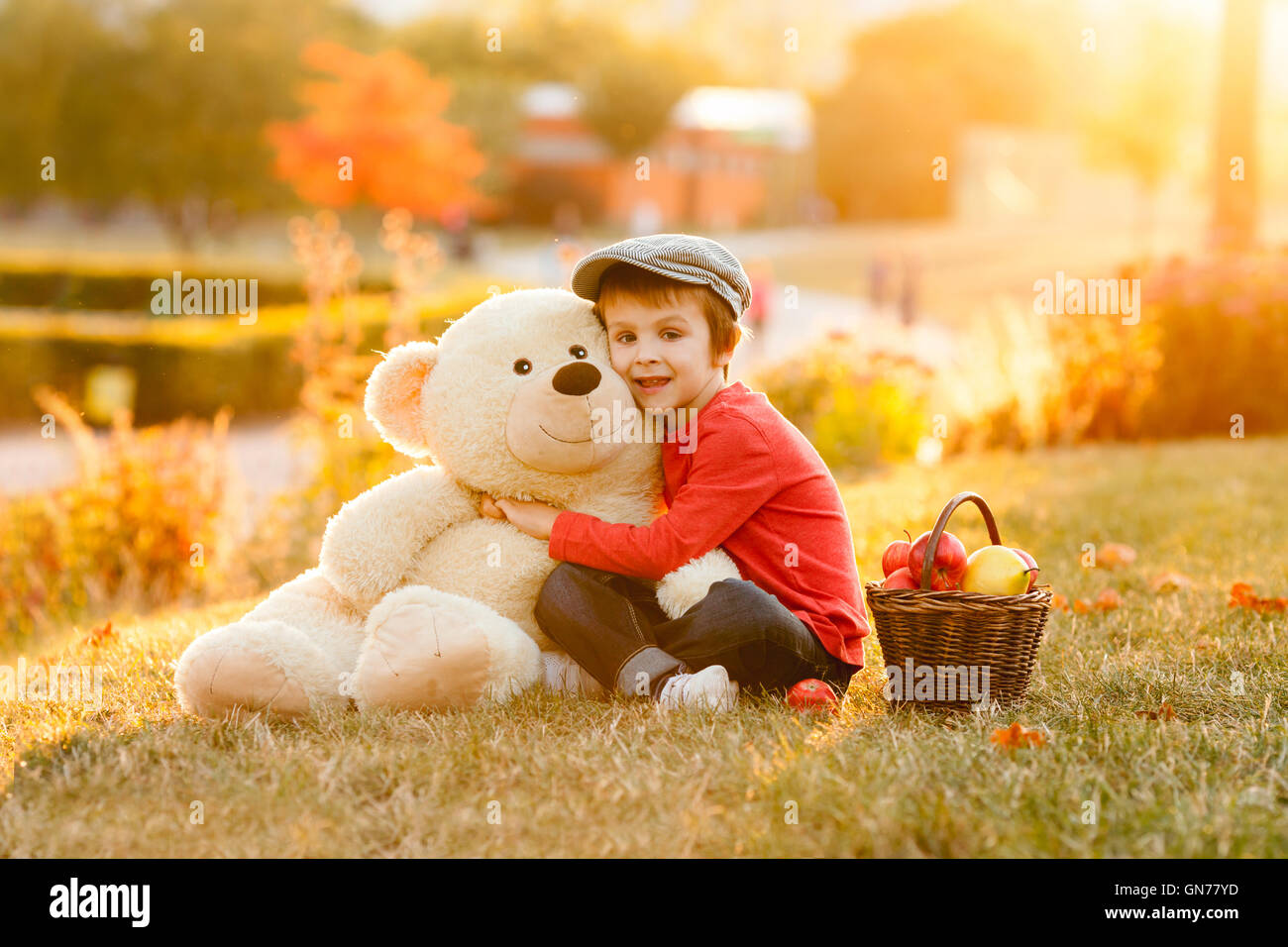Adorable little boy with his teddy bear friend in the park on sunset ...