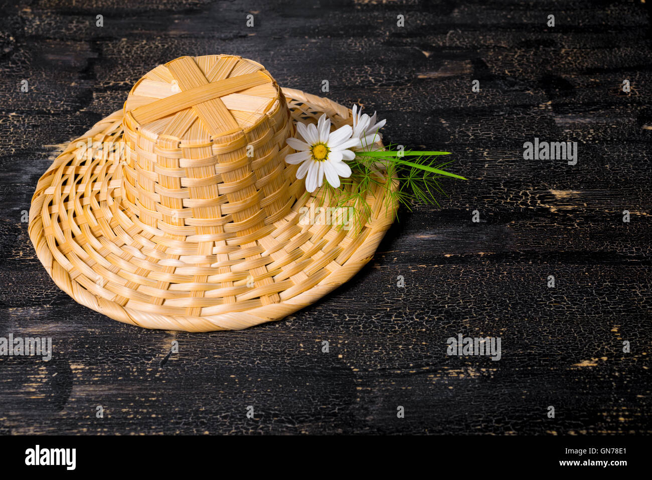 straw hat with daisies flower on black cracks background, close up Stock Photo