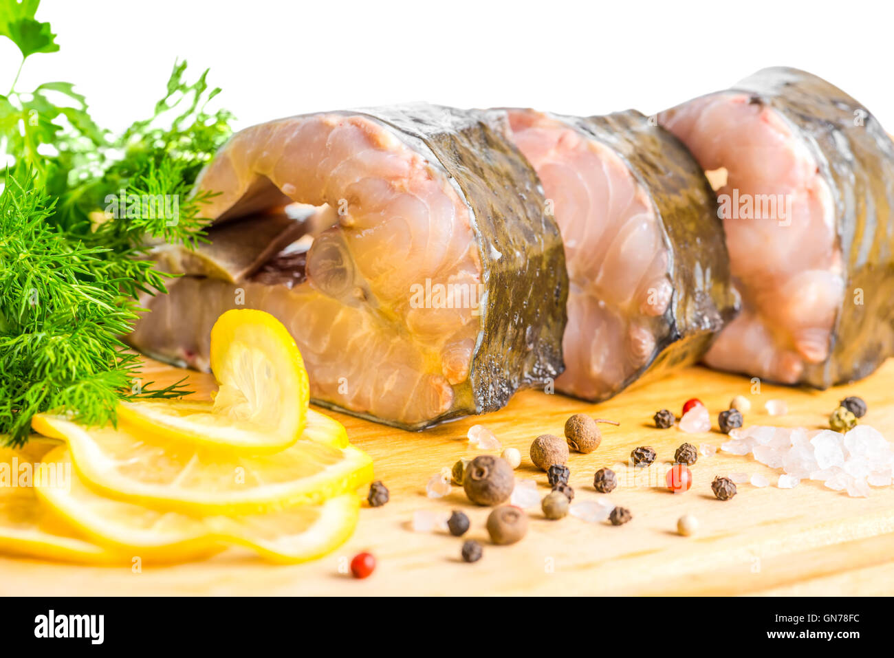 raw fillet steak of sturgeon fish with greens, lemon, different peppers and salt, isolated on white background, closeup Stock Photo