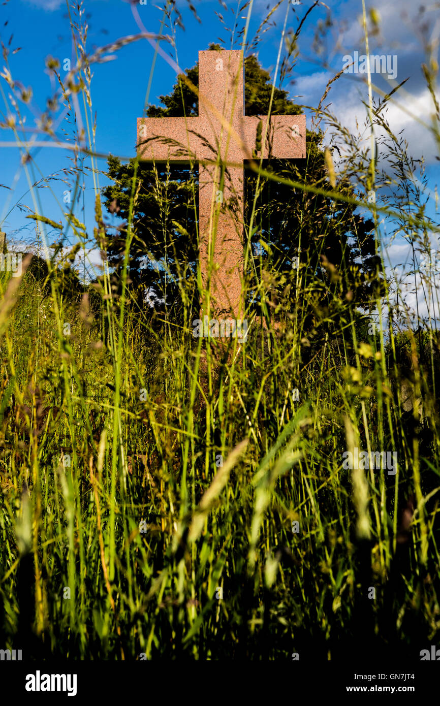 Headstone cross in long grass Stock Photo