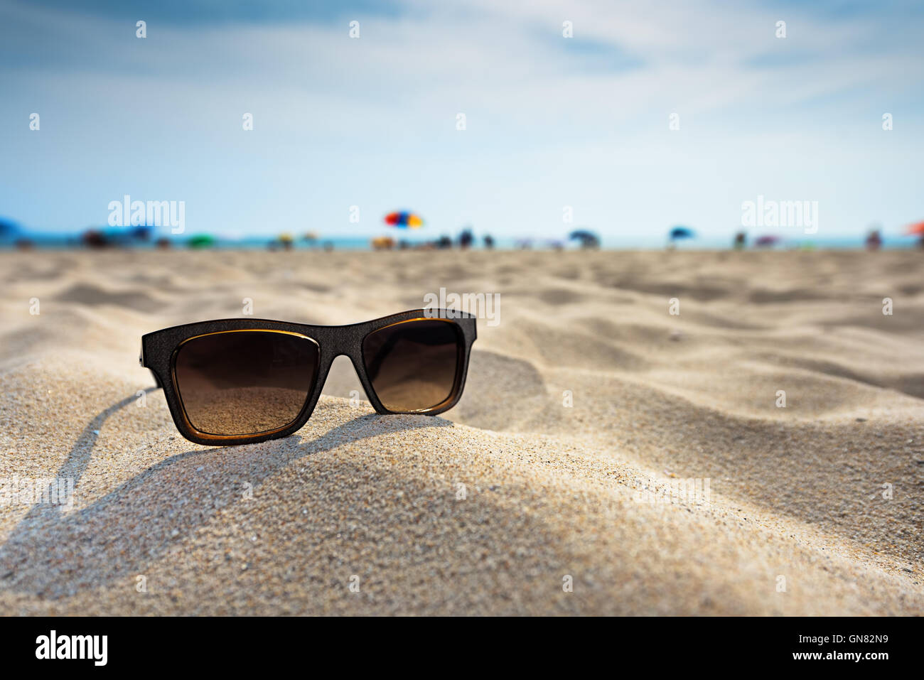 Sun glasses lie on a beach near the sea. Stock Photo