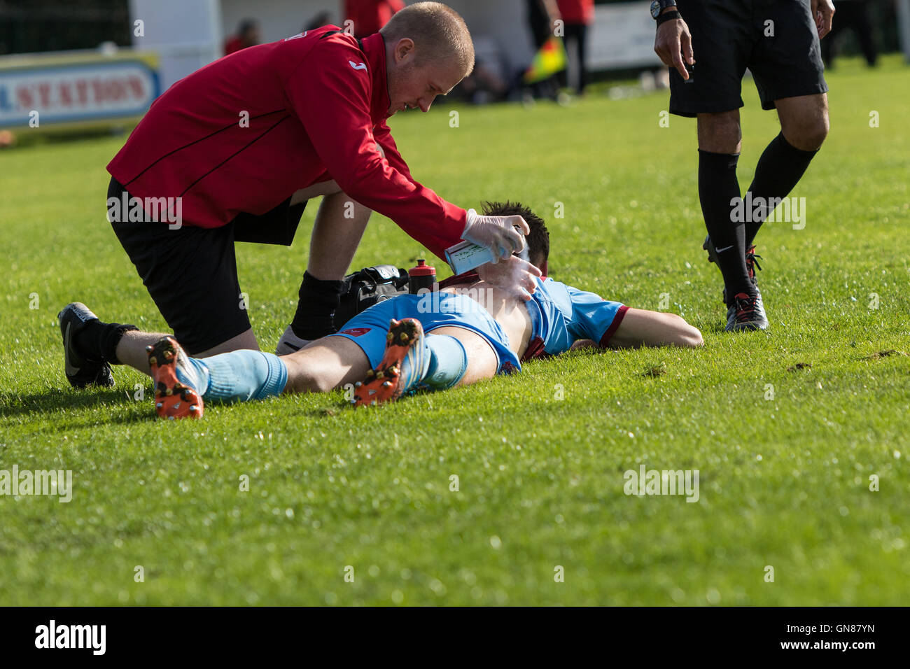 Football player receiving treatment and first aid from the club Physio Stock Photo